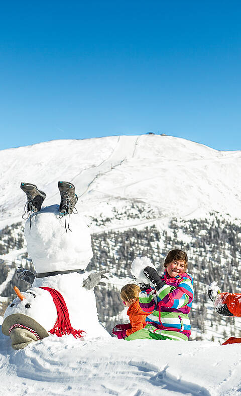 Katschberg_Kinder haben Spaß im Schnee mit Schneemann 